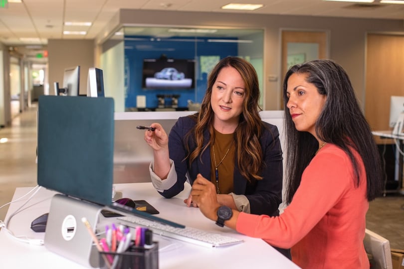 Two businesswomen assessing deductions data on a laptop.