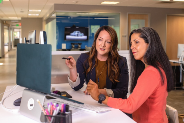 Two businesswomen assessing deductions data on a laptop